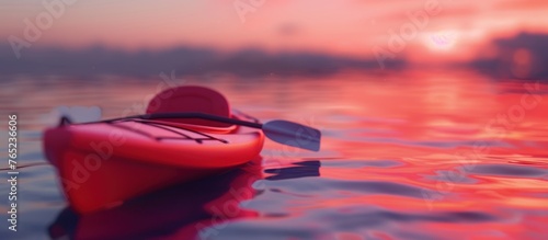 Red plastic kayak in calm water at sunset photo