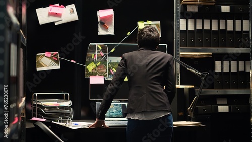 Vászonkép Police investigator looking at clues board in incident room, analyzing forensic evidence to uncover new investigation details