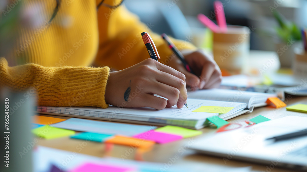 A close-up of a non-binary person's hands taking notes during a ...
