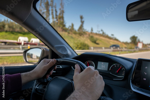 Driver hands on the steering wheel. Man driving a car on the highway, with motion blurred by speed.