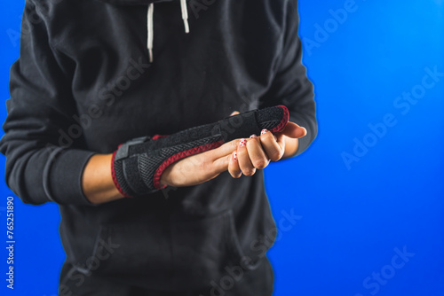 woman posing with a splint on her middle finger over blue background  injuries treatment. High quality photo