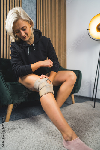 a young blond woman recovering from injuries at home and using a knee brace. High quality photo