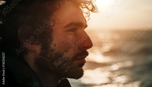A man with a beard standing next to the ocean. photo
