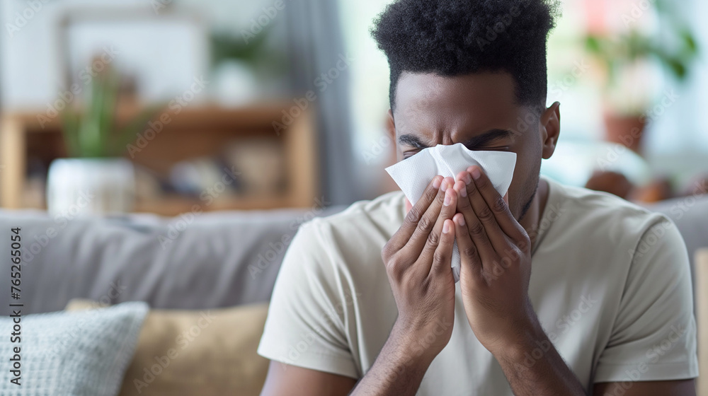 A man sick with a cold or allergies with a tissue held up to his nose.  - obrazy, fototapety, plakaty 