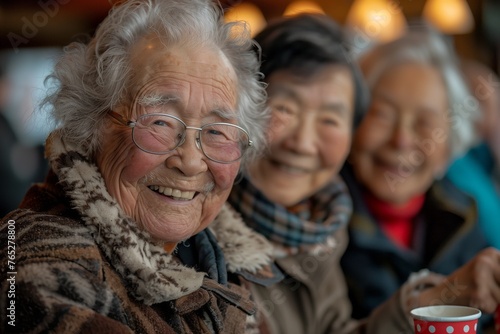 Three elderly women are happily smiling for the camera, seated at a table and sharing a fun event. They are wearing hats and there are tin cans and tableware around