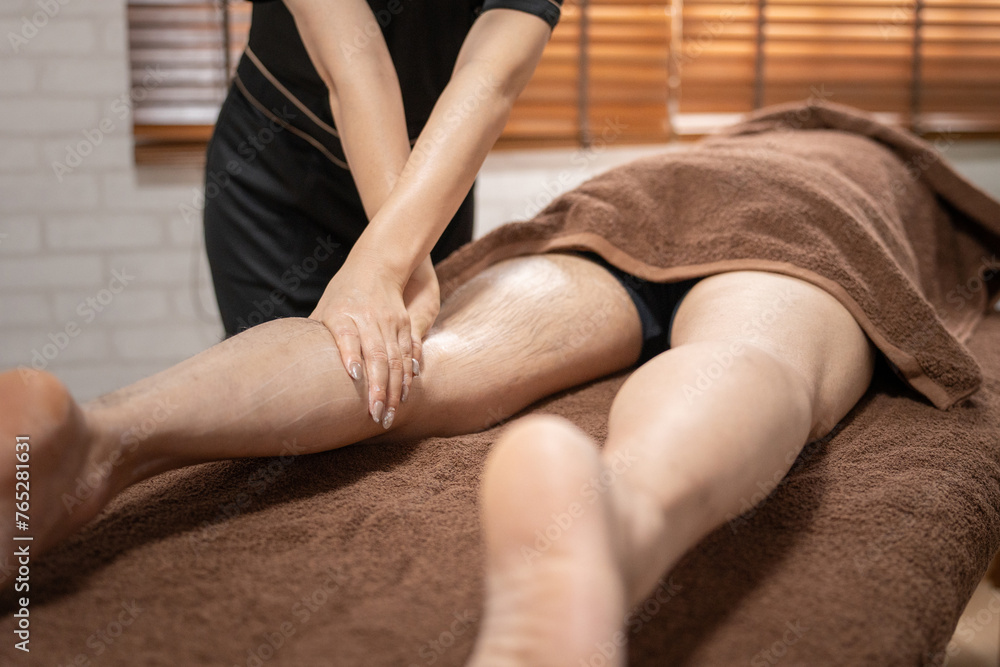 Obraz premium メンズエステ・脱毛サロンで足をマッサージするエステティシャンと男性
