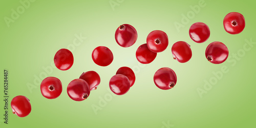Fresh red cranberries flying on green background
