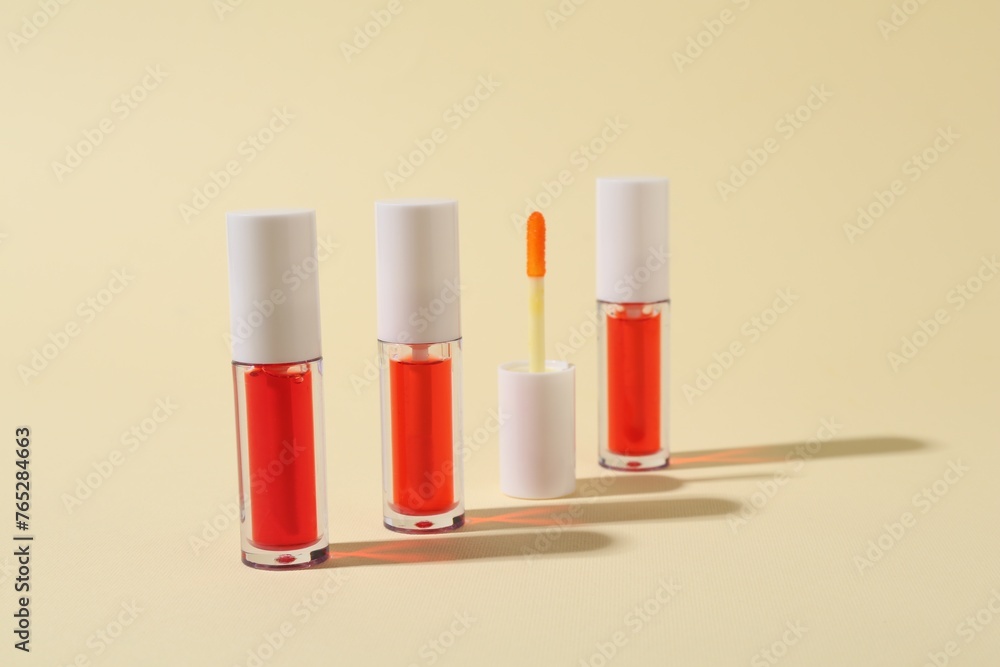 Bright lip glosses and applicator on beige background Bright lip glosses and applicator on beige background