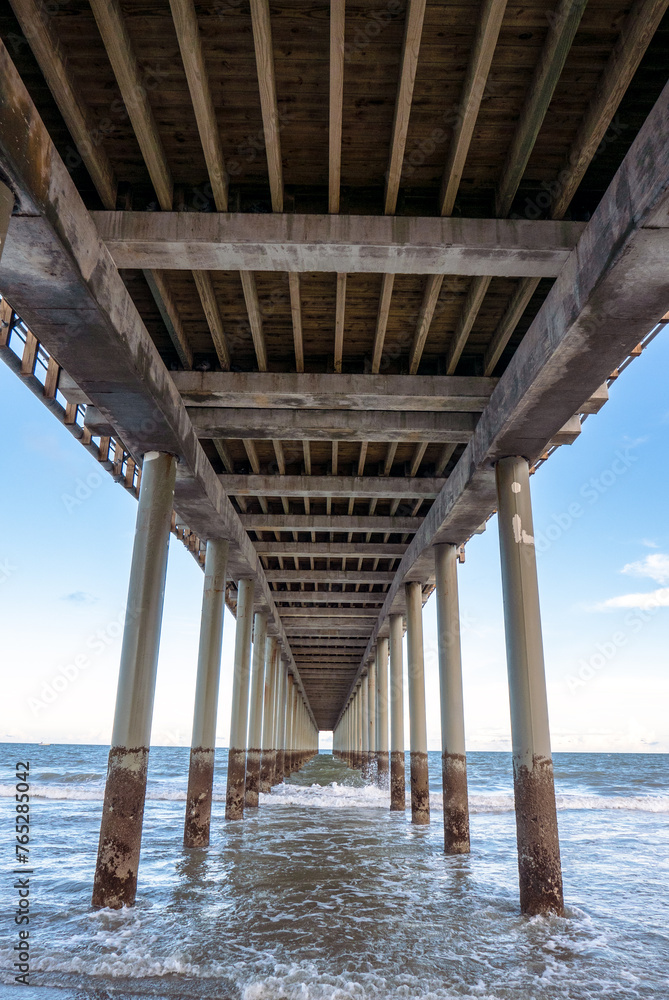 Pier stretches into the sea, framing coastal architecture and ocean.