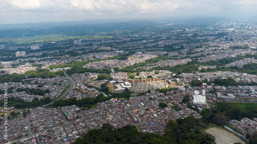 Naklejka premium Aerial view of the city of Armenia, Quindío, Colombia. Buildings in the city of Armenia between trees and the green mountains in the background