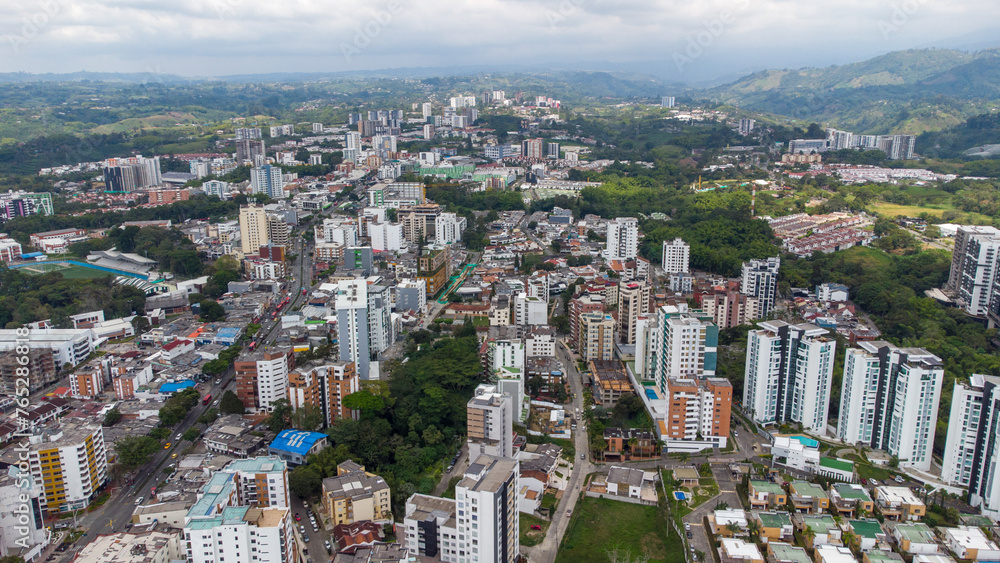 Naklejka premium Aerial view of the city of Armenia, Quindío, Colombia. Buildings in the city of Armenia between trees and the green mountains in the background