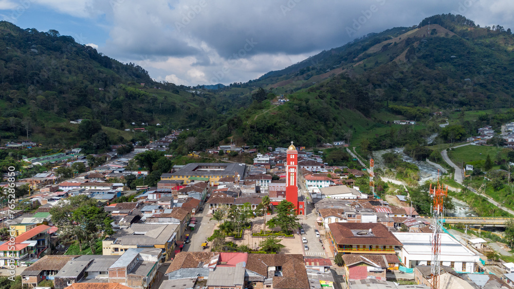 Fototapeta premium Aerial view of the green mountains and the river in the municipality of Pijao, Quindío, Colombia. Pijao, city without rush. Main park and church of Pijao.