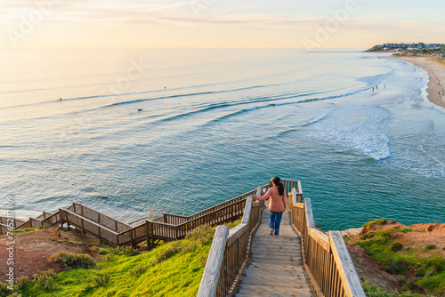 Woman descends the South Port Beach stairs captivated by the spectacular sea view during sunset, Port Noarlunga, South Australia photo