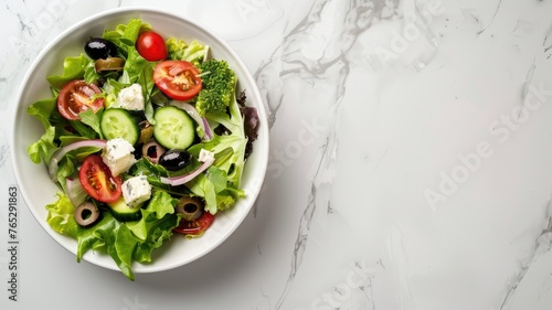 Overhead view of Greek salad in a bowl - Top view image showcasing a fresh Greek salad with ripe tomatoes, olives, and feta served on a white bowl