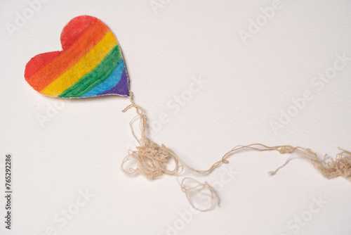 corazón de tela pintado como bandera del orgullo gay, simulando volar con hilos 