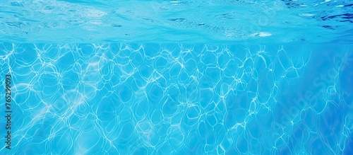 A closeup view of the liquid aqua in the swimming pool reveals an electric blue hue with mesmerizing patterns, reflecting the sky and clouds above