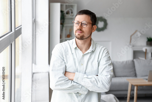 Handsome man in stylish eyeglasses at home