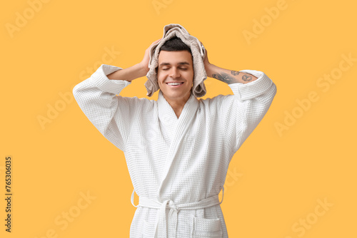Portrait of handsome young man in bathrobe and towel on yellow background © Pixel-Shot