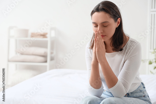 Young woman praying in bedroom