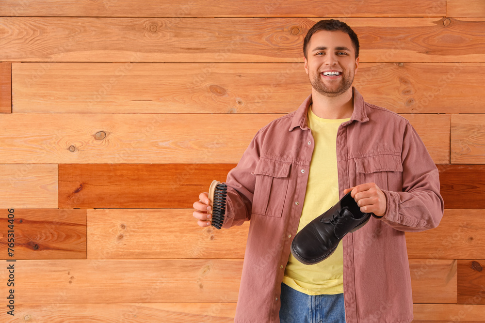 Male shoemaker with brush and boot on wooden background Male shoemaker with brush and boot on wooden background