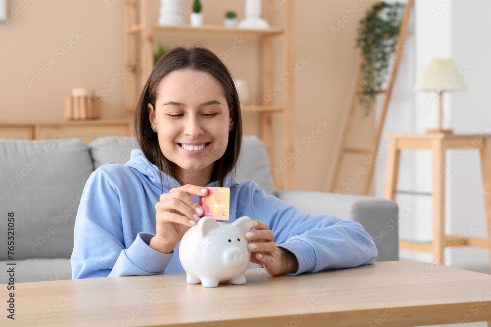 Pretty young woman with credit card and piggy bank at home Pretty young woman with credit card and piggy bank at home