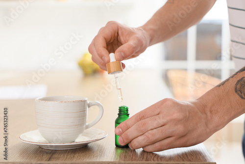 Young man dropping CBD oil ...