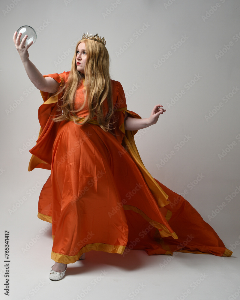 Full length portrait of plus sized woman blonde hair, wearing historical medieval fantasy gown, golden crown of royal queen. Standing pose holding crystal seer orb, isolated studio background. Full length portrait of plus sized woman blonde hair, wearing historical medieval fantasy gown, golden crown of royal queen. Standing pose holding crystal seer orb, isolated studio background.