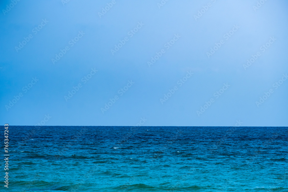 background for summer vacation concept. Nature of the beach and sea, summer with sunlight, sandy beach The sparkling sea water contrasts with the blue sky	
