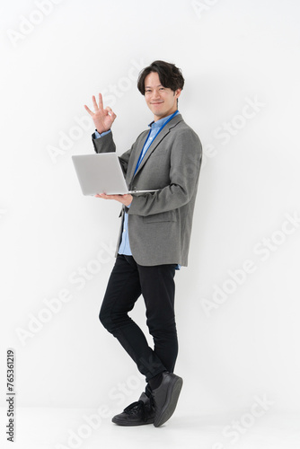 ノートパソコンを持ってサインをする男性