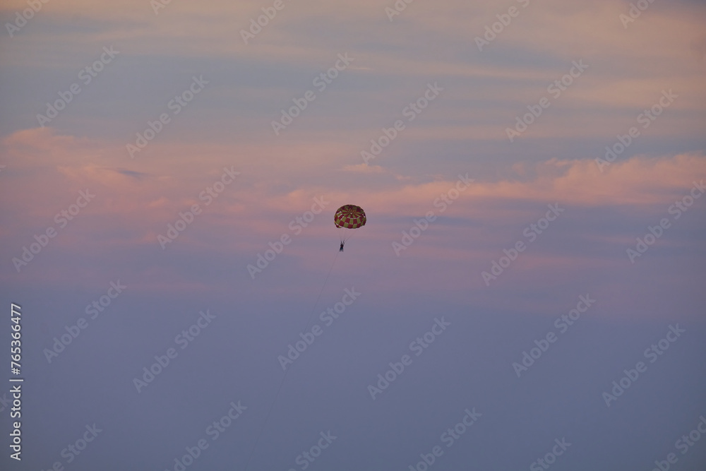 Tourists fly in the sky on a parachute against the sunset near Phu Quoc Island of Vietnam. Tourists fly in the sky on a parachute against the sunset near Phu Quoc Island of Vietnam.