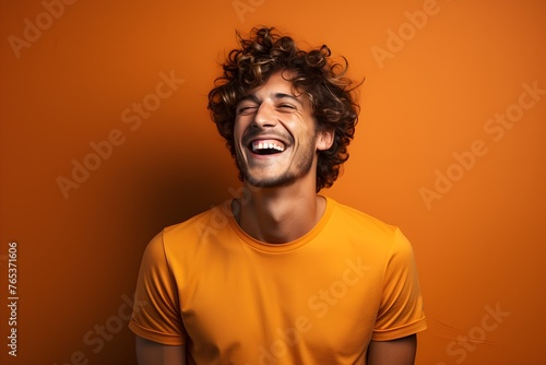Young adult man laughing agaisnt solid color background © VisualVanguard