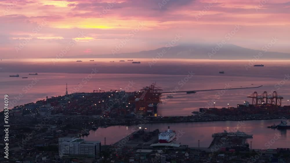 Aerial view of cargo seaport at twilight. Pink color sky and sea surface. Heavy cranes in logistic hub. Manila, Philippines Aerial view of cargo seaport at twilight. Pink color sky and sea surface. Heavy cranes in logistic hub. Manila, Philippines