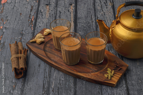 Fresh milk masala tea or Indian Kadak Chai.  Herbal tea in glass cups. Locally called mini cutting chai or cutting chai or masala chai. Indian chai in glass cups with metal kettle and other masalas
