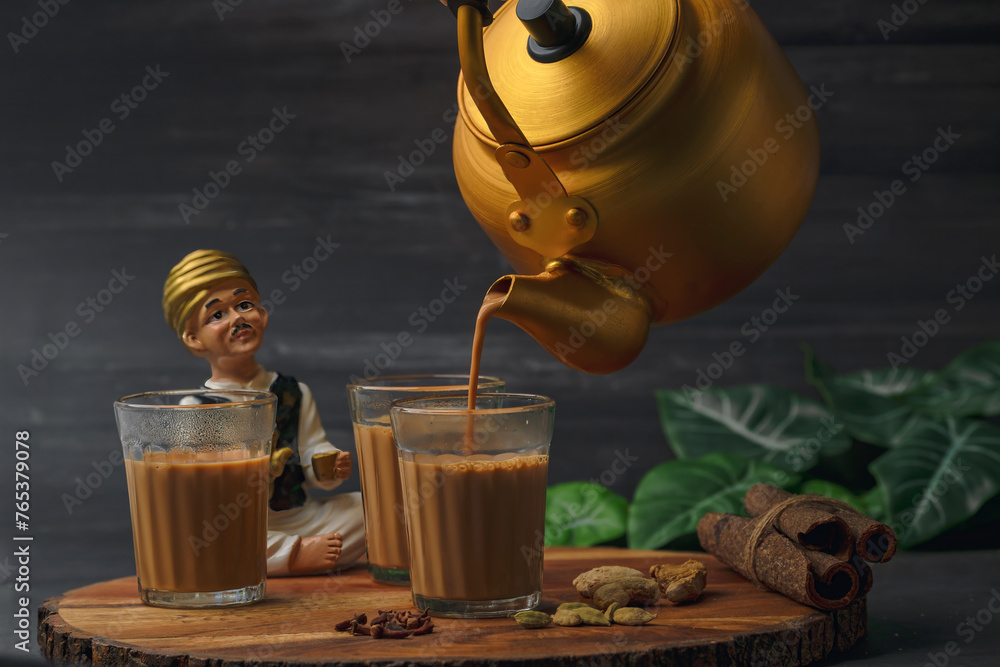 Fresh milk masala tea or Indian Kadak Chai. Herbal tea in glass cups. Locally called mini cutting chai or cutting chai or masala chai. Indian chai in glass cups with metal kettle and other masalas