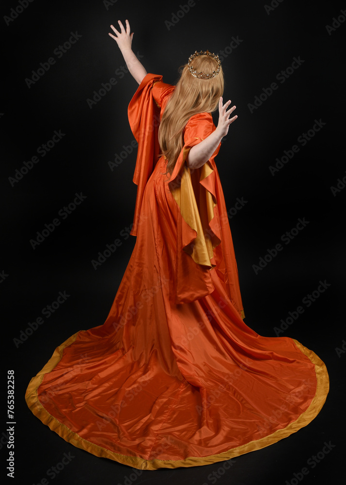Obraz premium Full length portrait of plus sized woman blonde hair, wearing historical medieval fantasy gown, golden crown of royal queen. Standing pose, walking away in silhouette, isolated dark studio background.