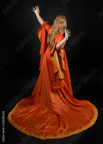 Full length portrait of plus sized woman blonde hair, wearing historical medieval fantasy gown, golden crown of royal queen. Standing pose, walking away in silhouette, isolated dark studio background.