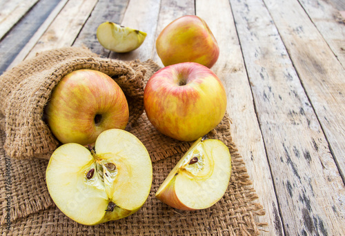 Fresh apples in burlap sack on wooden table background