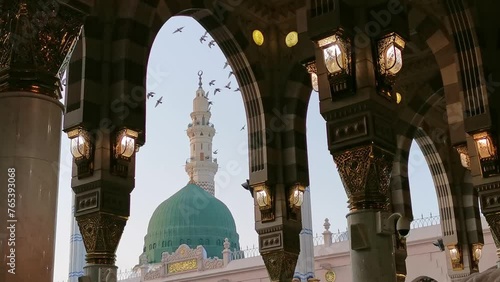 Closeup view green dome and Moorish pattern arches with a flock of birds fly over at Nabawi mosque in Al Madinah, Saudi Arabia. 