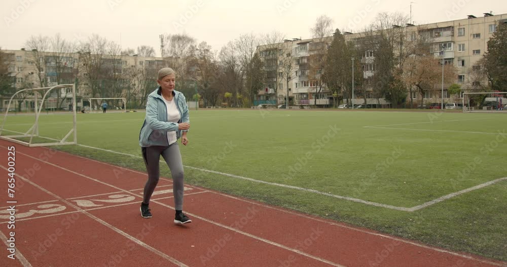 Old fit woman running marathon at stadium arena Old fit woman running marathon at stadium arena