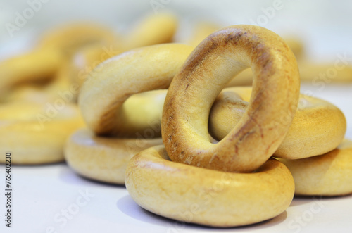 Small heap of golden bagels on white surface. Macro photography