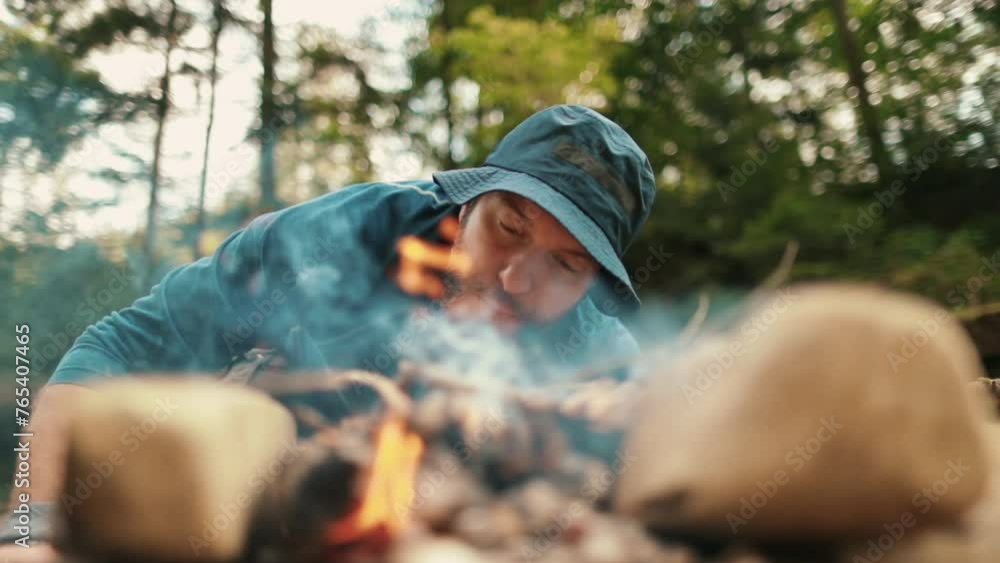 A man, a tourist, a traveler lights a fire, blows on coals. Single tourist hikes in wild nature. A man, a tourist, a traveler lights a fire, blows on coals. Single tourist hikes in wild nature.