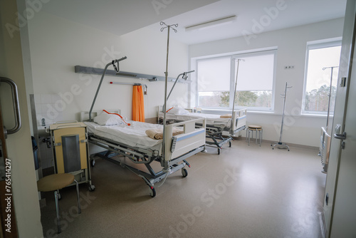 Valmiera, Latvia - March 20, 2024 - A hospital room with two empty beds, IV stands, a chair, large windows with a view, and various medical equipment.