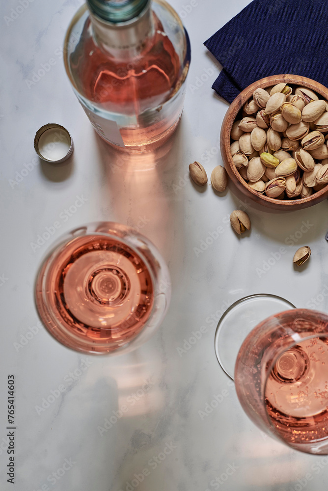 Fototapeta premium two glasses of rose wine and bowl of pstachios