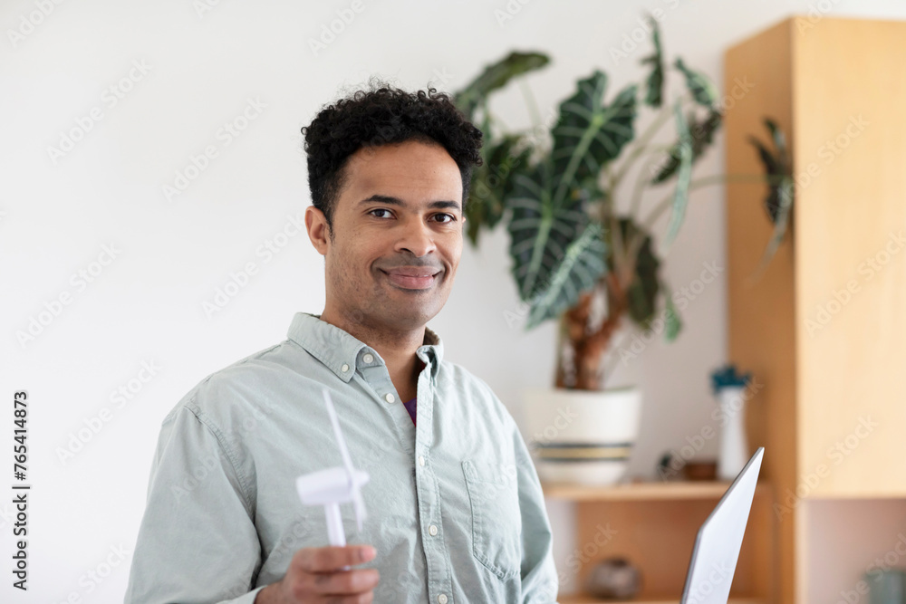 Young man, mixed race, with a windmill and laptop in an office Young man, mixed race, with a windmill and laptop in an office