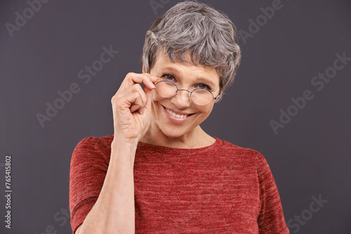 Happy, portrait and senior woman with glasses in studio for vision, optometry or frame sale on grey background. Eye care, testing or face of old lady model smile for pensioner, spectacles or discount