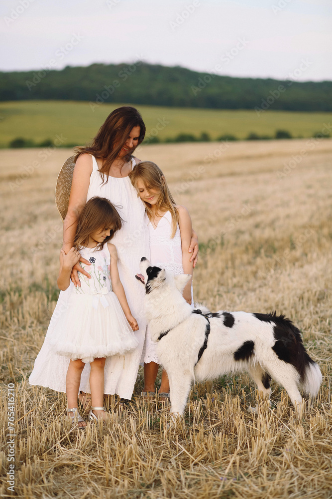 Happy mother and daughter in summer dresses and their dog