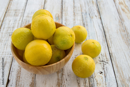 Fresh lemons in a wooden bowl on wooden background