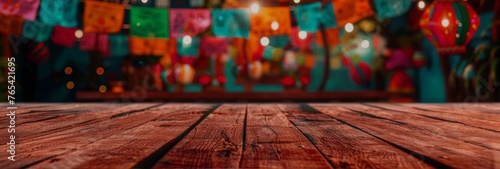 An empty old wooden table with festive decor and Mexican holiday lighting in soft focus in the background. A festive banner with more space for text or product. photo