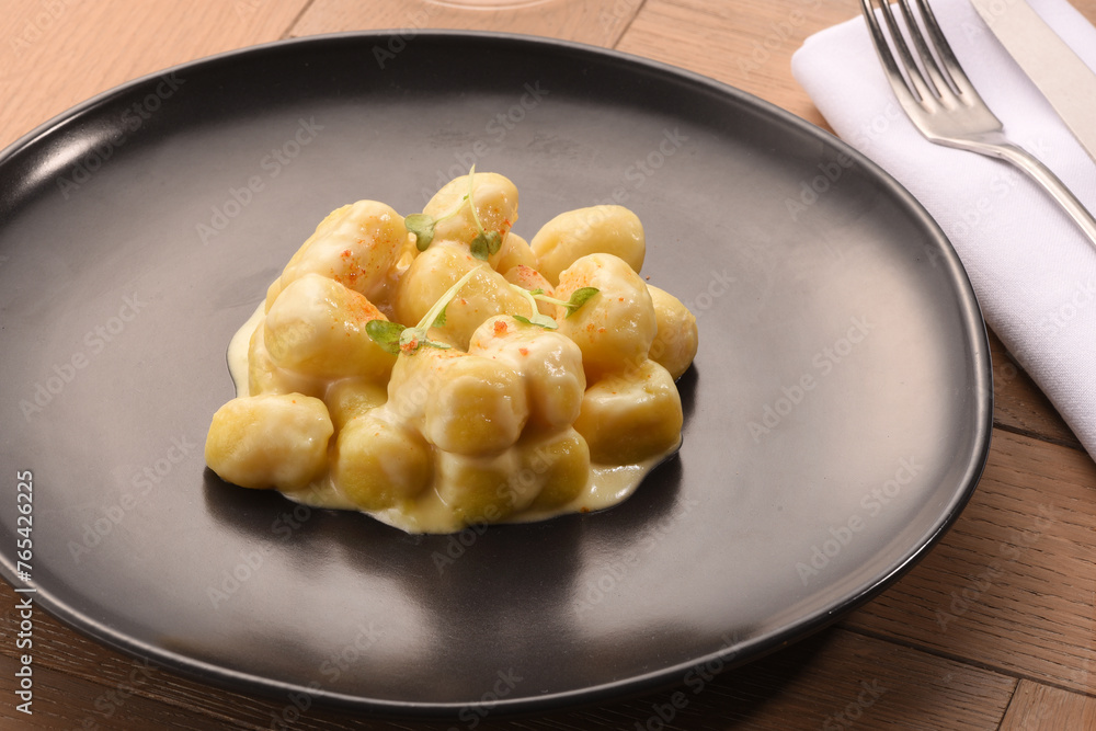 Italian gnocchi with white sauce on black plate Italian gnocchi with white sauce on black plate