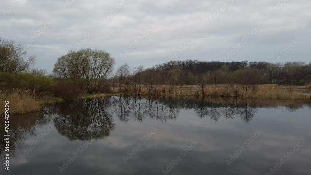 Jesienny dzień nad jeziorem z odbijającym się niebem w tafli wody Jesienny dzień nad jeziorem z odbijającym się niebem w tafli wody